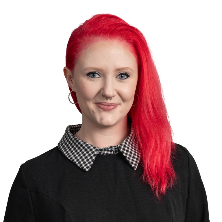 Person with bright red hair wearing a black top and a black-and-white checkered collar, facing the camera.