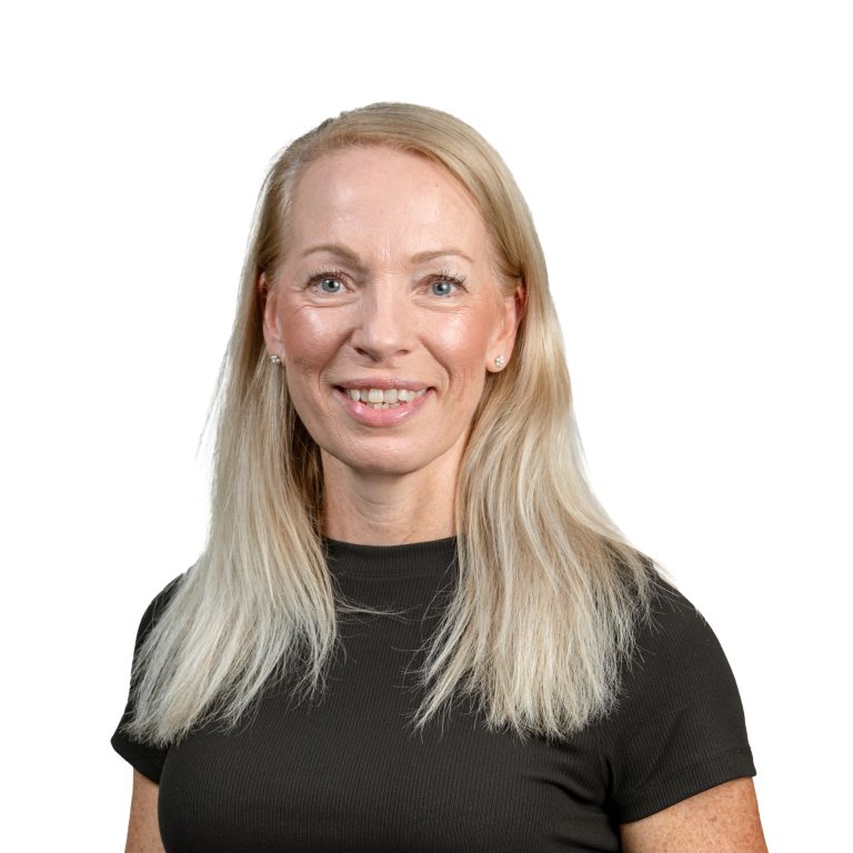 Close-up portrait of a smiling blonde woman in a black top, shoulders visible.