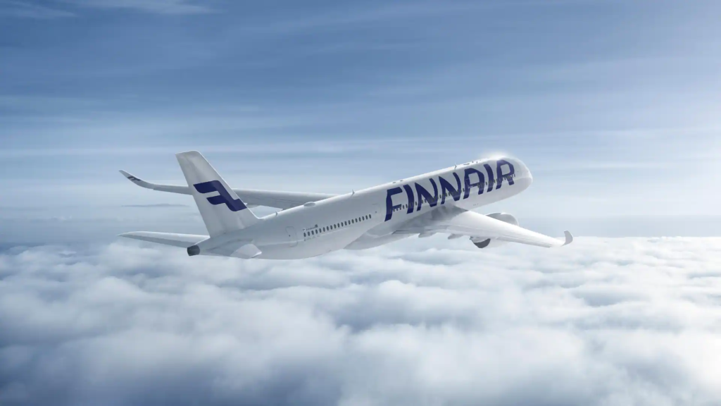 Finnair passenger airplane ascending above the clouds in a clear blue sky.