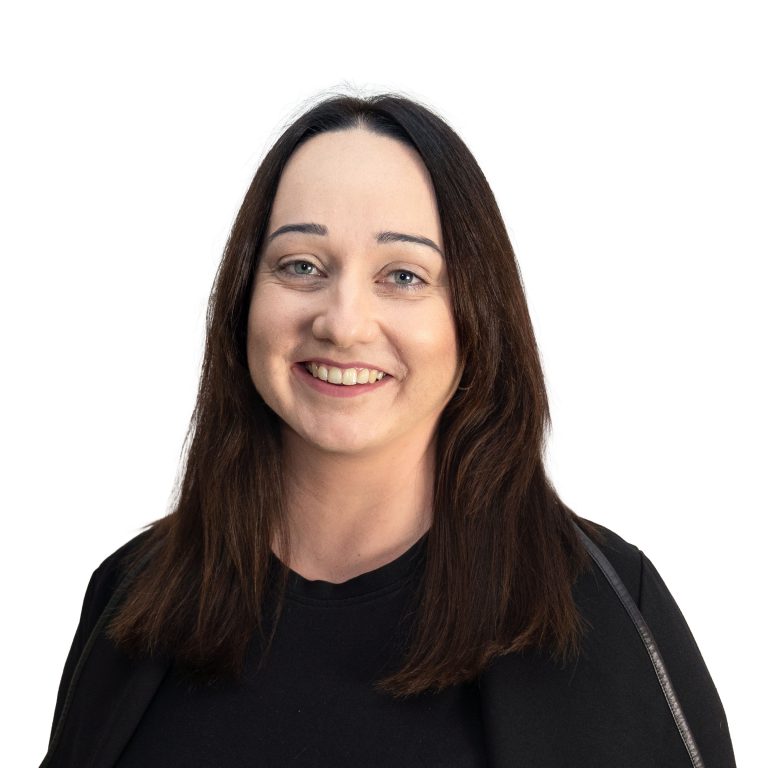 Close-up portrait of a smiling woman with dark hair wearing a black top against a white background