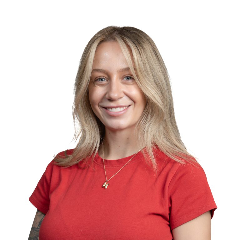 Smiling woman with blonde hair wearing a red shirt, cropped at shoulders